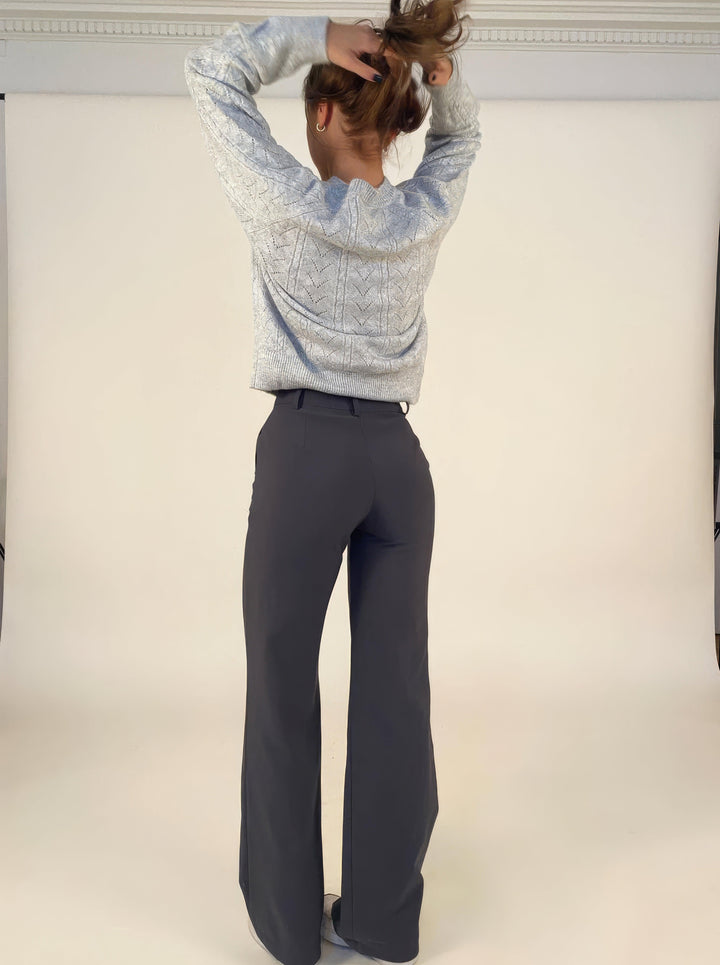 Side view: Woman posing in elegant high-waisted wide-leg trousers, showing fluid silhouette.