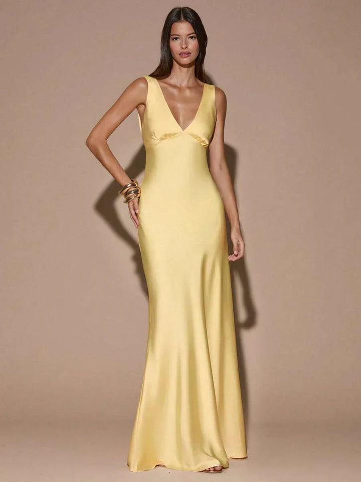 Elegant light yellow V-neck backless maxi evening dress with mermaid hem. Perfect formal gown for wedding guests & special occasions.