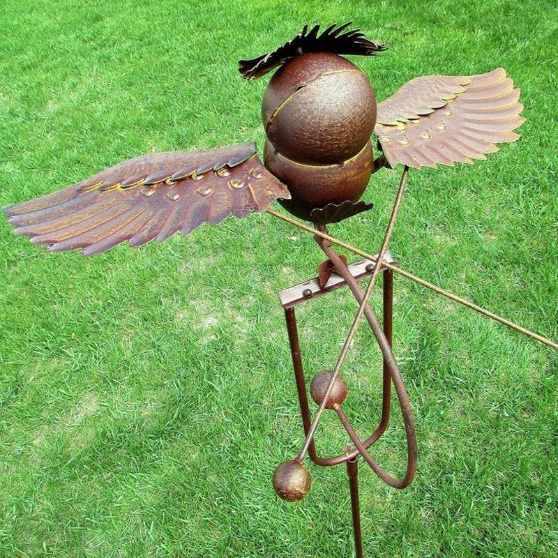 Wrought iron bird statue wind spinner, a decorative metal outdoor ornament for garden or patio accent.