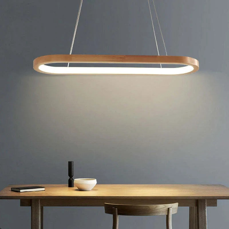 Sleek oval LED pendant light, made from wood and acrylic, enhances dining room decor.