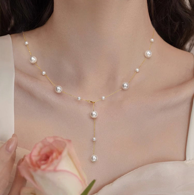 Gold chain lariat necklace featuring genuine white pearl drops, a timeless and luxurious women's accessory.