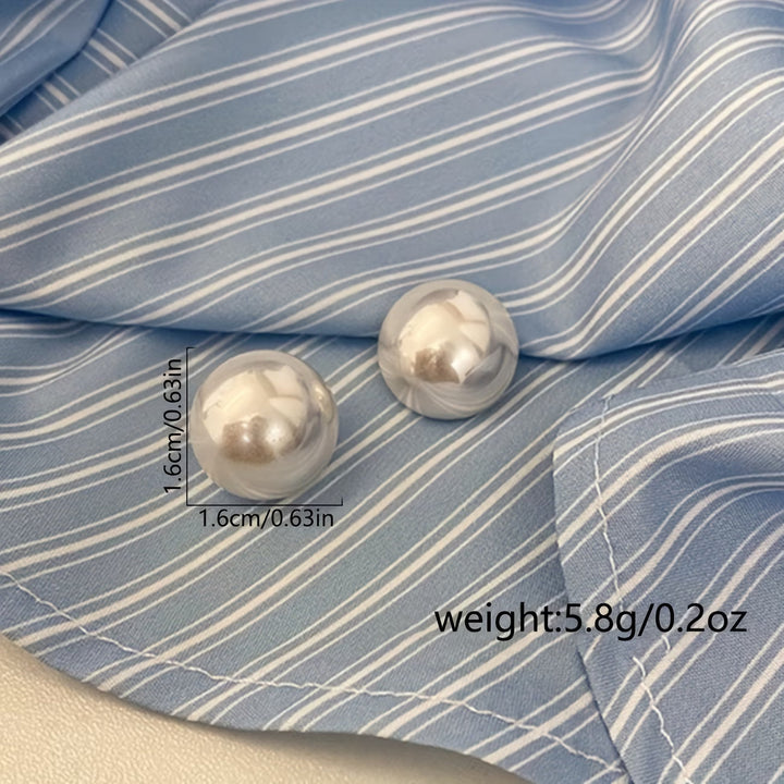 Close-up of elegant white pearl stud earrings, a classic women's jewelry piece. Fashionable & hypoallergenic.