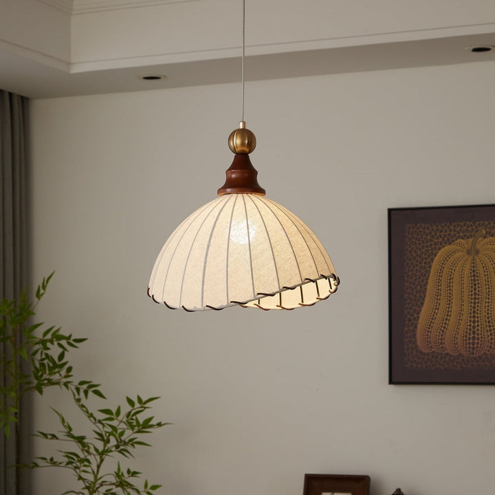Modern rustic pendant light with a graceful fabric shade, gold finish, and natural wood.