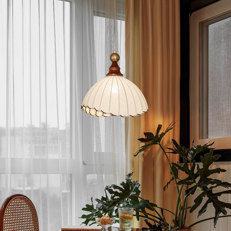 Designer pendant light with a soft fabric shade, luxurious gold accents, and wood trim.
