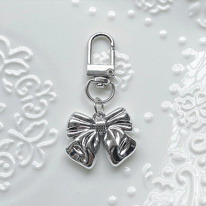 Delicate pearl-white bow charm pendant for women, adding an elegant touch to any necklace, bracelet, or bag.