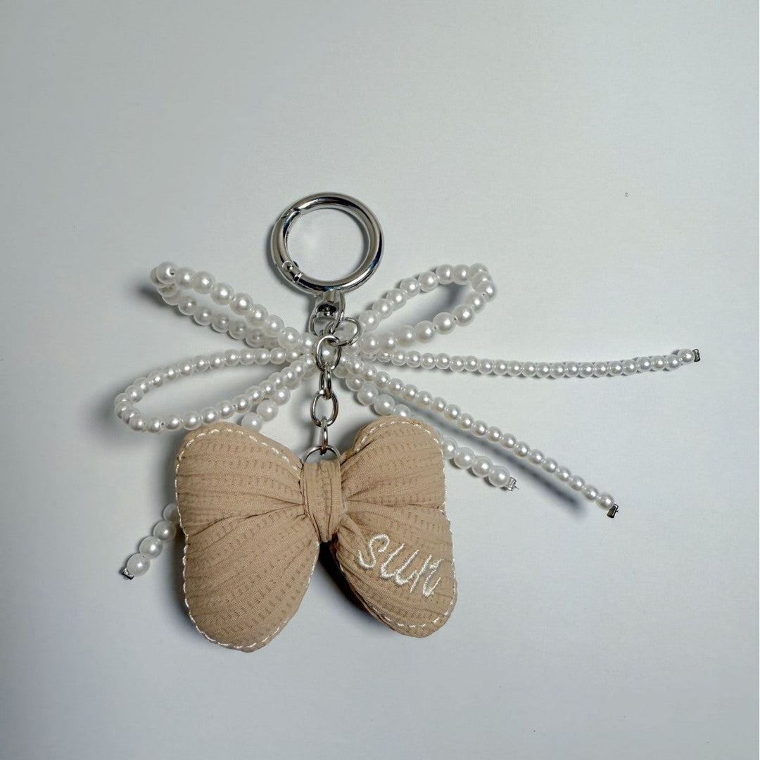 Fashionable butterfly bag charm with pearls, an elegant women's accessory.
