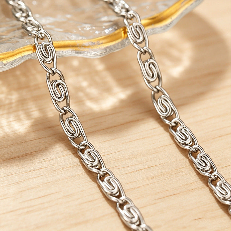 Woman wearing an elegant silver-tone woven chain bracelet, a sophisticated fashion accessory.
