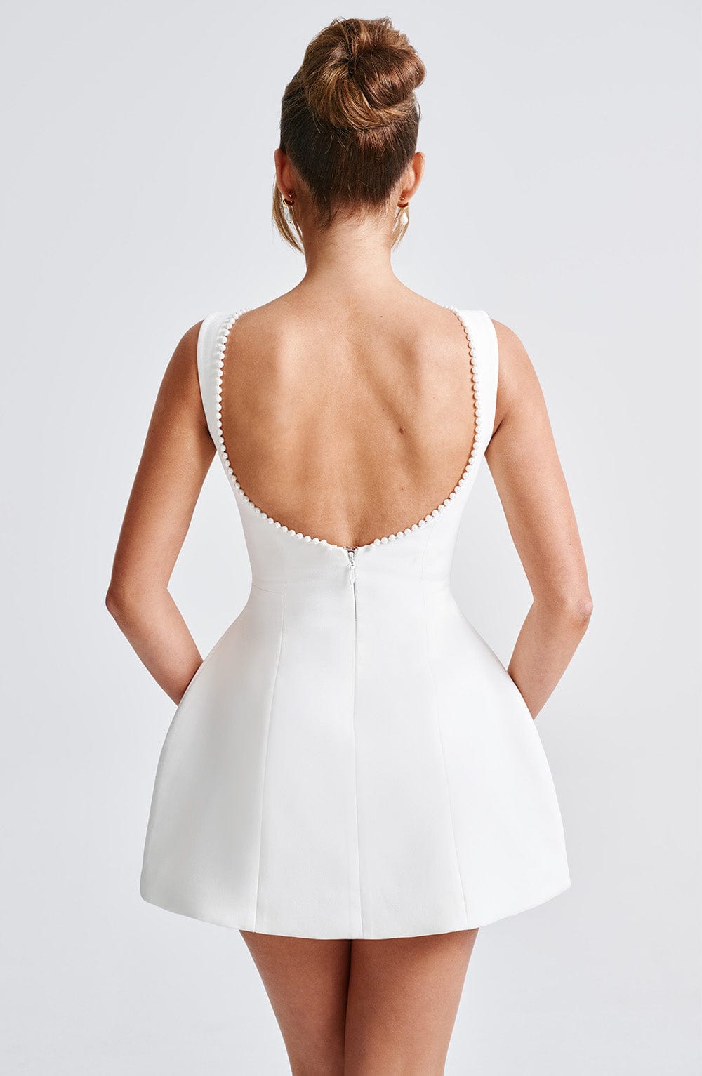 Woman in a chic sleeveless mini dress, ideal as a wedding guest or elegant cocktail party outfit.