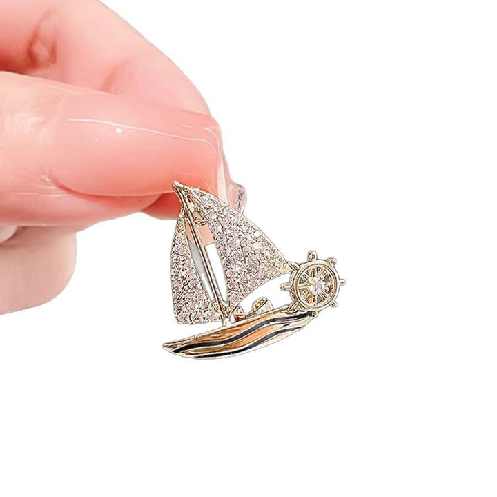 Women's elegant sparkling sailboat brooch pin, a chic nautical jewelry accessory.