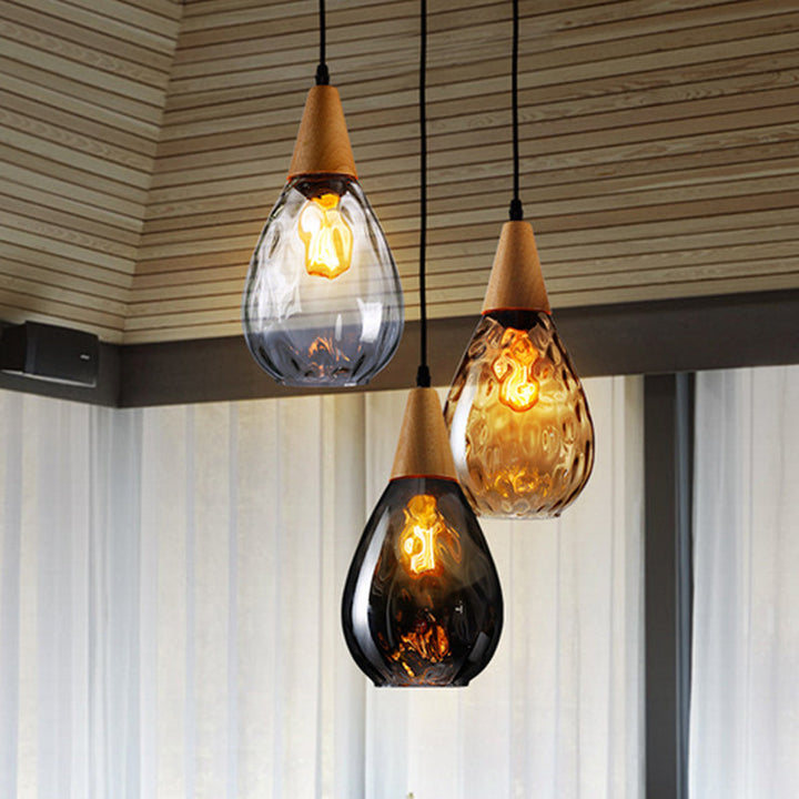 Elegant teardrop glass pendant light with wood accent. Modern ceiling lamp for stylish home decor.