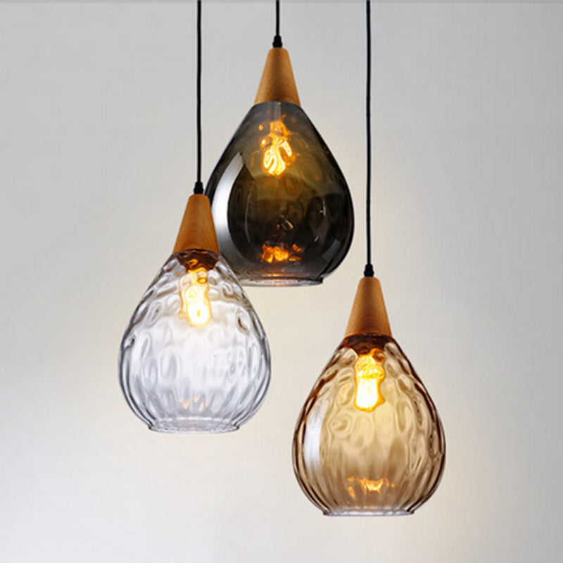 Close-up of elegant teardrop glass pendant light, showcasing clear glass and wood detail.
