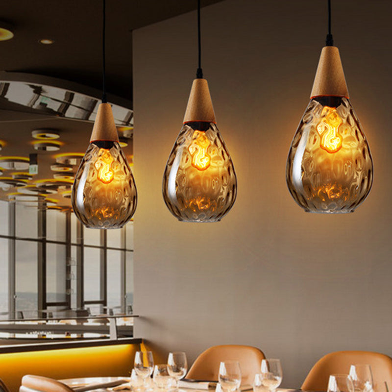 Teardrop glass pendant light, unlit, showcasing modern design & clear glass in daylight.