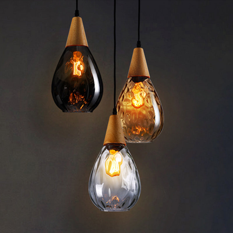 Modern teardrop glass hanging lamp with elegant wood detail, perfect for kitchen or dining.
