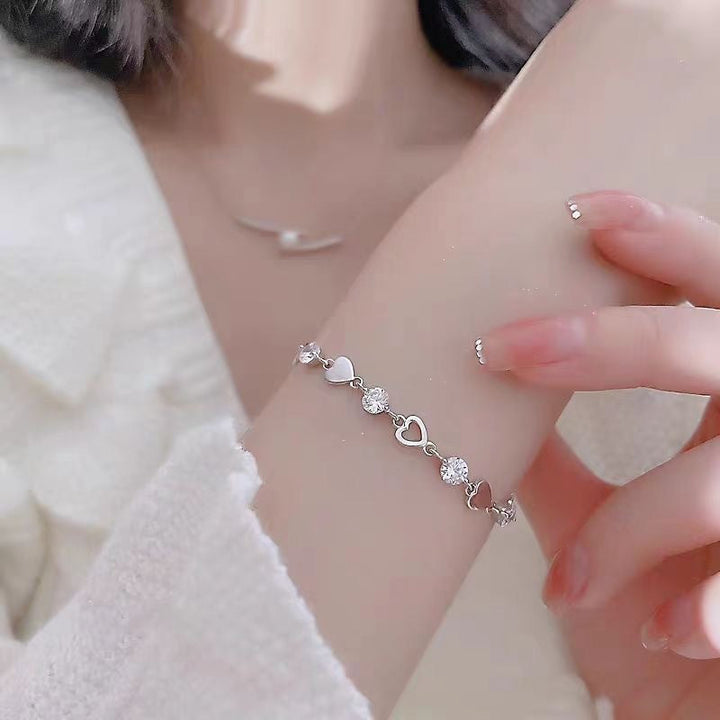 Dainty white & gold heart charm bracelet with shimmering crystals. Elegant and adjustable women's jewelry.