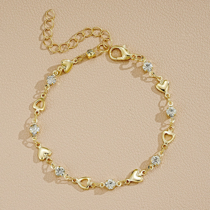 Close-up: Elegant white & gold heart charm bracelet. Intricate design with sparkling crystals for women.
