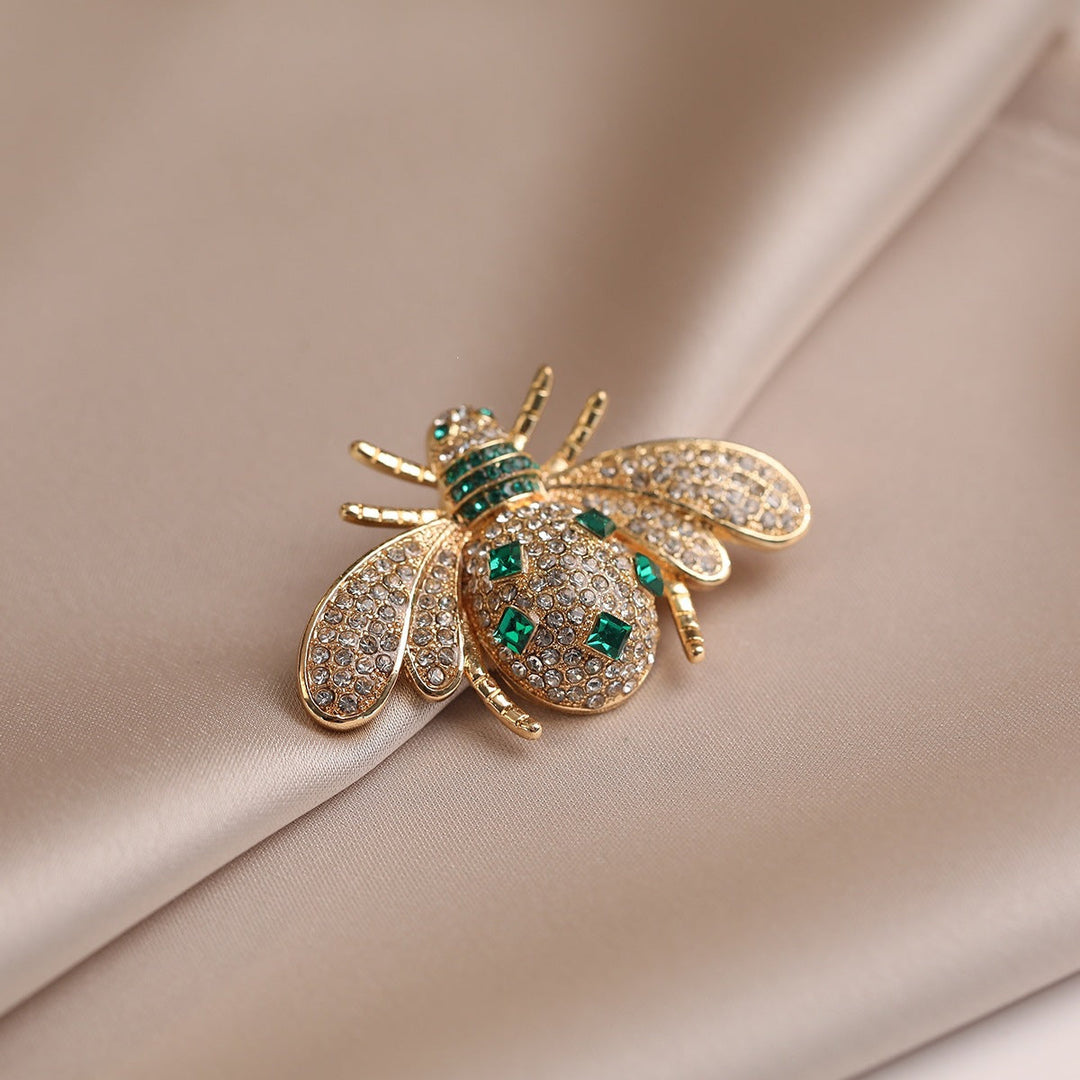 Sparkling rhinestone bee brooch for women, featuring an elegant gold finish. Nature-inspired insect design accessory.