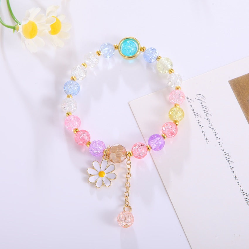 Close-up of an elegant women's bracelet: sparkling glass beads and a charming flower pendant.