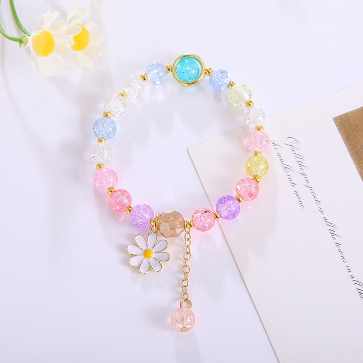 Close-up of an elegant women's bracelet: sparkling glass beads and a charming flower pendant.