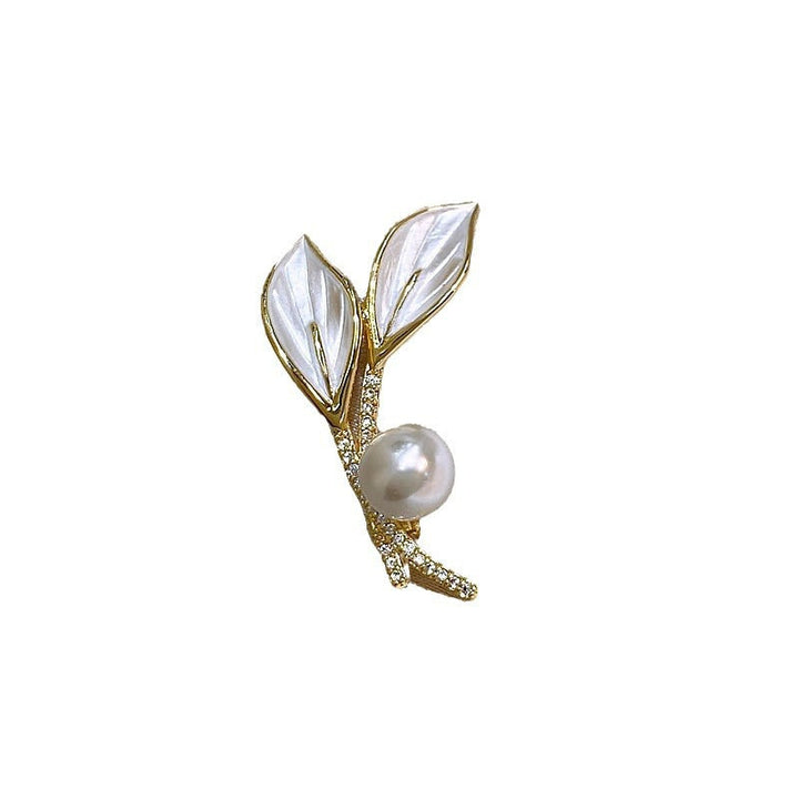 Close-up of an elegant women's brooch, showcasing radiant pearls and brilliant rhinestones on a branch motif.