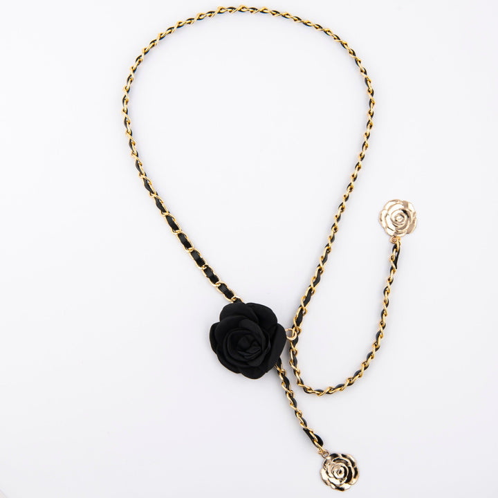 Close-up of elegant rose detail on a women's black chain belt, a stylish waist accessory.