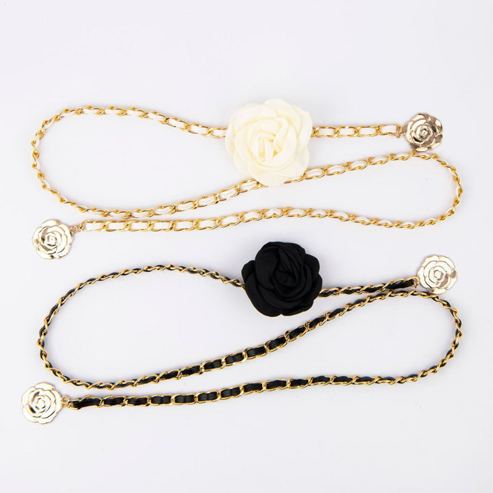 Women's elegant black chain belt with rose detail cinching a dress, a chic fashion waist accessory.