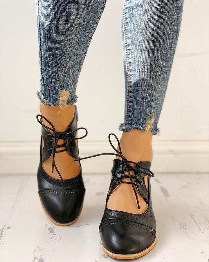 Close-up of classic women's brogue boots featuring intricate perforated details & sturdy block heel.
