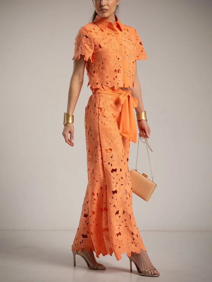 Stylish women's wedding guest outfit: elegant cutout lace top & comfortable wide-leg trousers set.