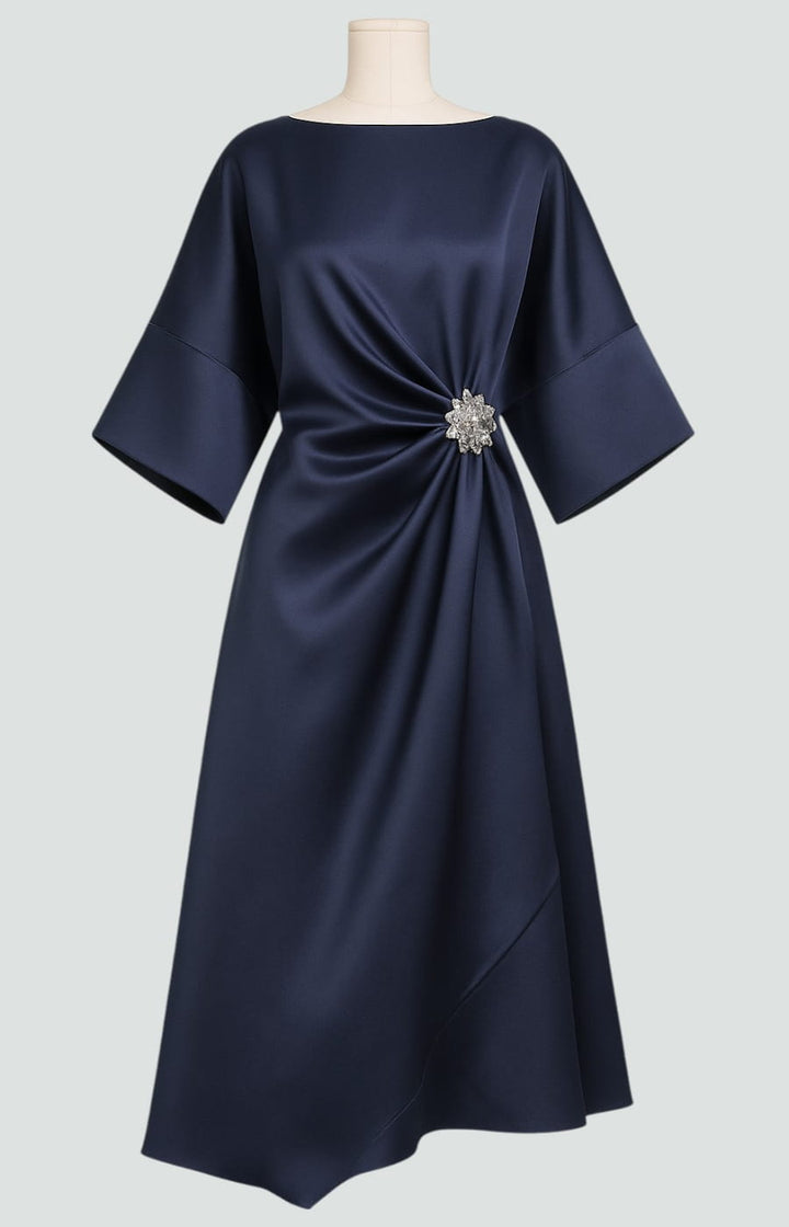 Elegant women's flowing maxi dress with intricate draping and a decorative brooch.