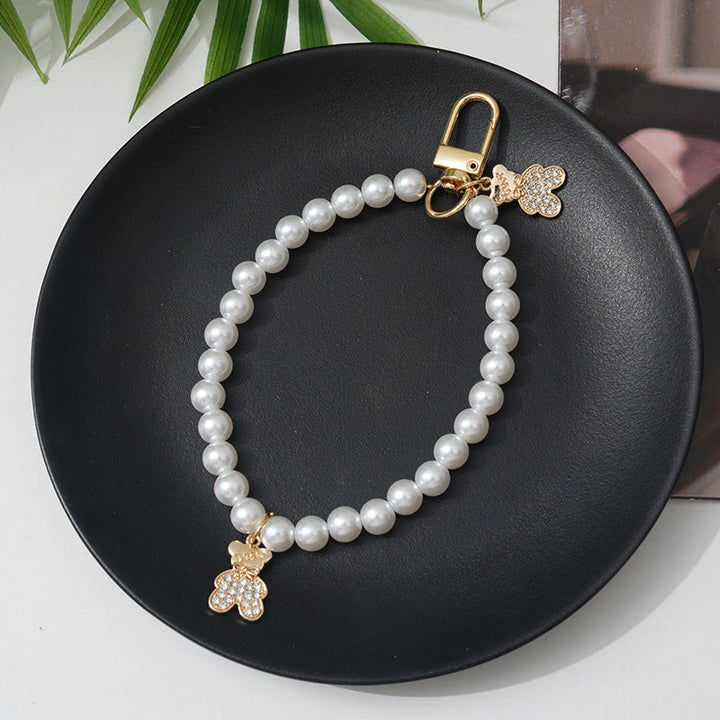 Lustrous faux pearl bracelet for women, adorned with a pretty bow charm and subtle rhinestones.