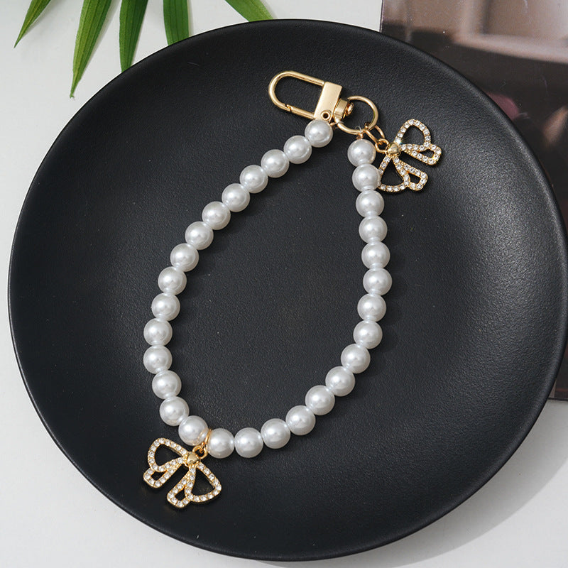 Adjustable women's faux pearl bracelet featuring a dazzling rhinestone bow, a sophisticated accessory.