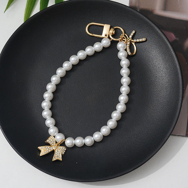 Delicate faux pearl bracelet for women, showcasing an elegant bow charm accented with clear rhinestones.