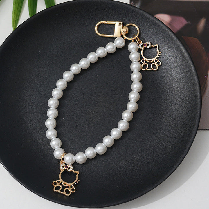 Close-up of a women's elegant faux pearl bracelet, highlighted by a shiny rhinestone bow charm.