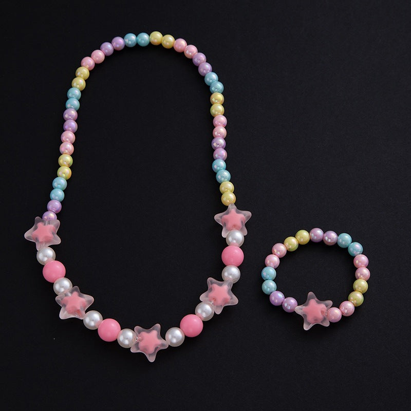 Elegant women's floral jewelry set, necklace & bracelet with pastel pearls, displayed on a vanity.