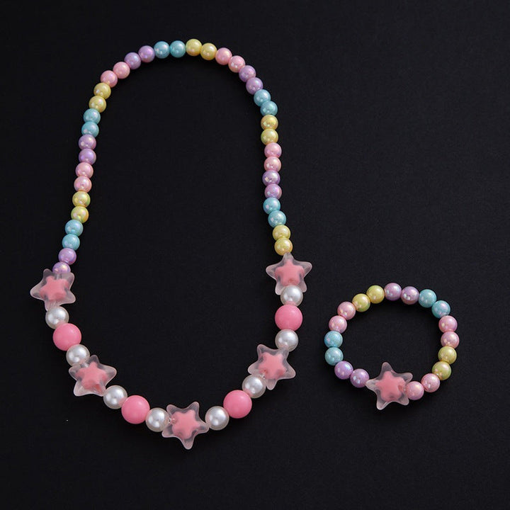 Elegant women's floral jewelry set, necklace & bracelet with pastel pearls, displayed on a vanity.