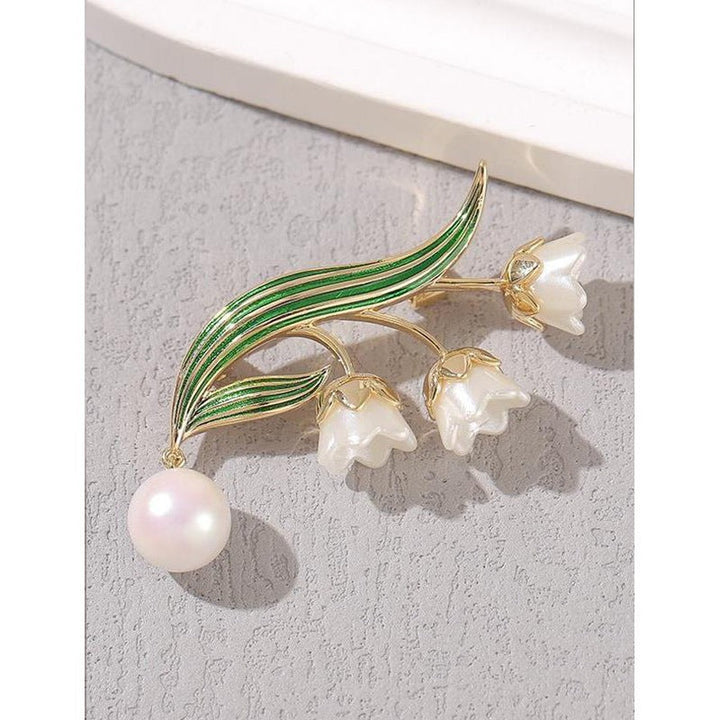 Detailed floral pin: elegant women's flower brooch featuring intricate petals & a shimmering pearl pendant.