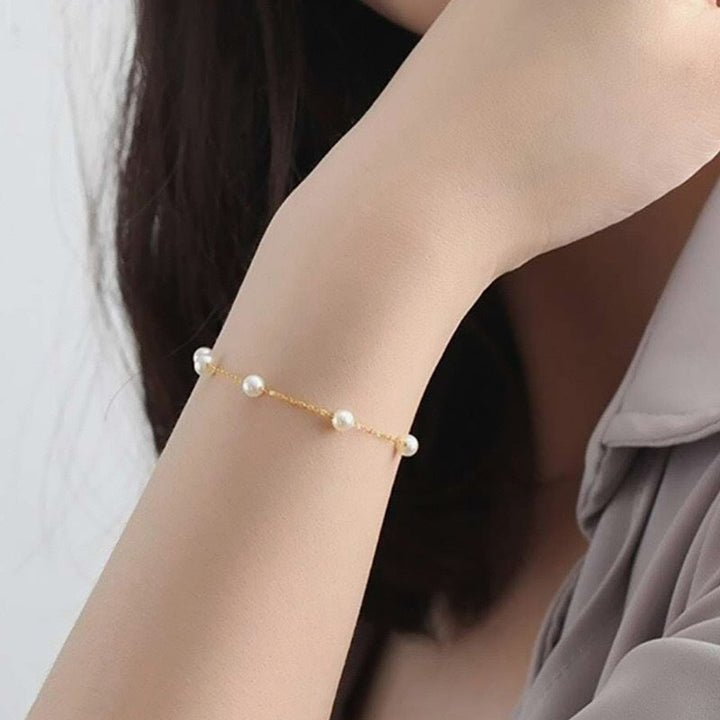 Elegant women's gold chain bracelet with delicate white pearls. A stylish and adjustable fashion accessory.