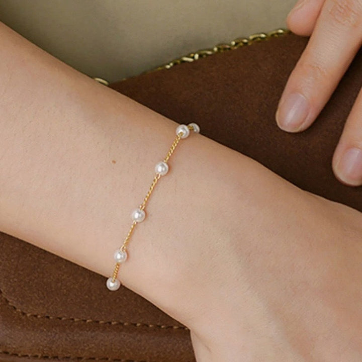 Close-up of delicate white pearls on an elegant gold chain bracelet for women. Perfect pearl jewelry gift.