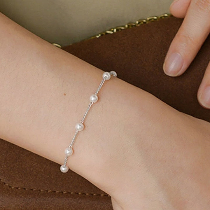 Dainty gold chain bracelet for women featuring lustrous white pearls. Elegant and adjustable pearl jewelry.