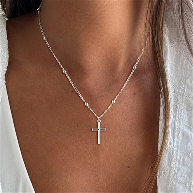 Close-up of a women's gold cross pendant, showcasing its elegant design and delicate chain, spiritual accessory.