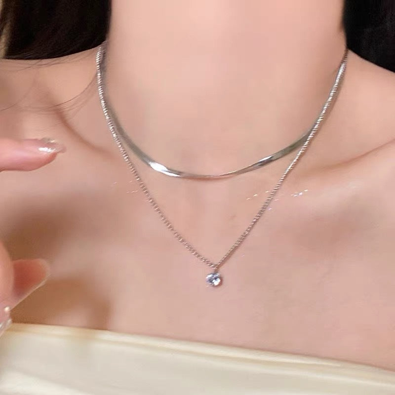 Close-up of a women's gold layered necklace, highlighting the delicate chains and elegant pendant detail.