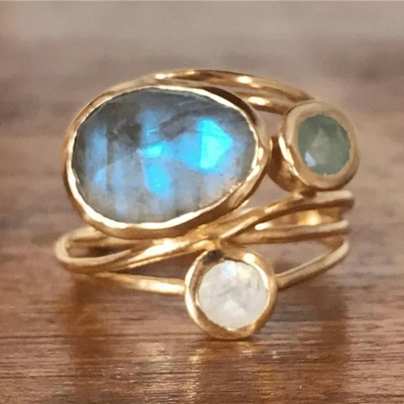 Elegant women's gold multi-stone ring with iridescent bezel-set gems, a fashionable statement jewelry piece.
