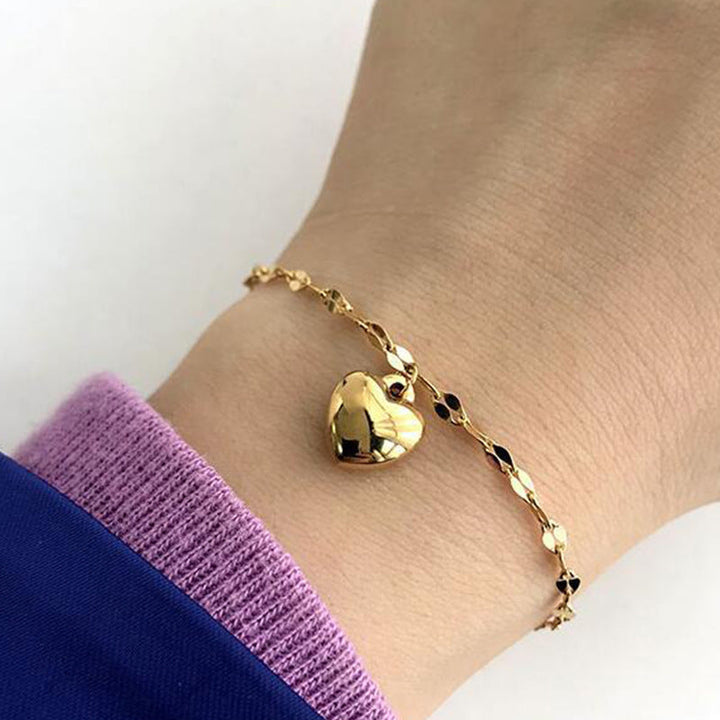 Elegant women's gold tone heart charm bracelet, adjustable for everyday wear. Dainty fashion jewelry gift.