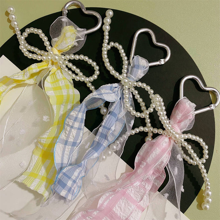 Elegant women's heart keychain with pearl & ribbon charm, perfect accessory for bags & purses.
