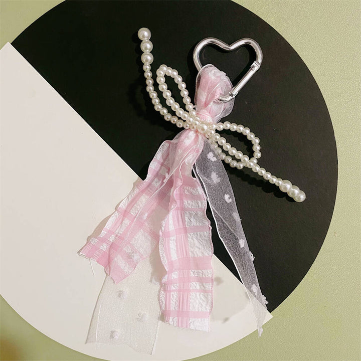 Women's elegant heart keychain with pearl and ribbon charm, a fashionable accessory for bags and keys.