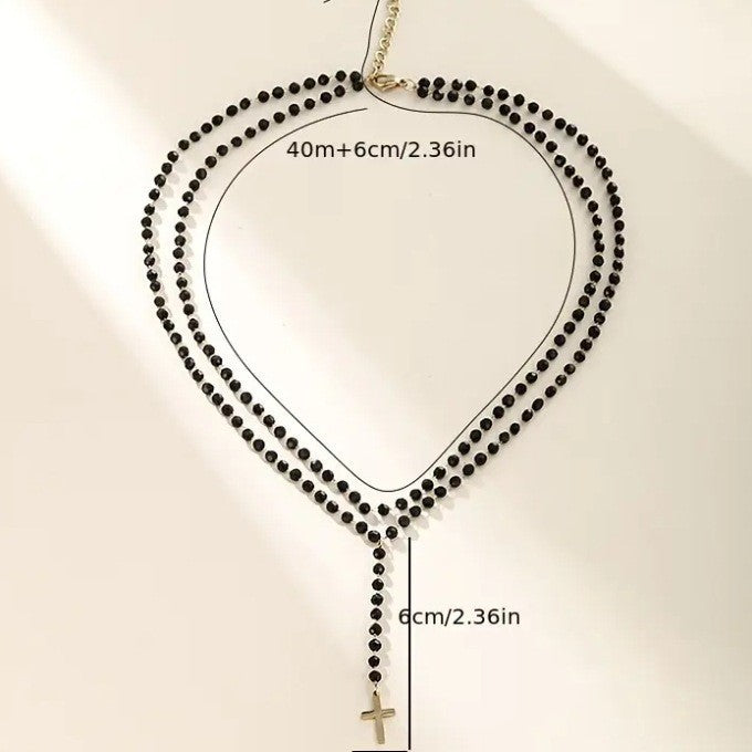 Close-up of a women's layered necklace with sparkling beads, featuring a prominent cross and a dainty star pendant.