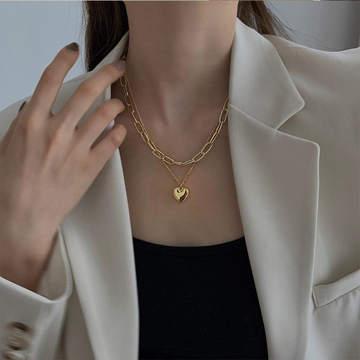 Gold-tone layered chain necklace featuring multiple heart charms, a stylish accessory for women.