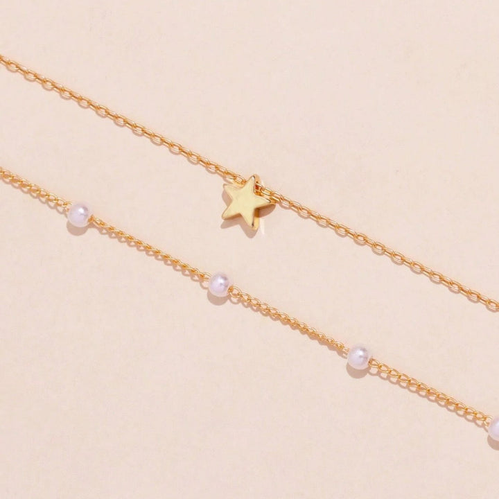 Women's gold layered necklace with shimmering pearls and a small star pendant, an elegant and versatile piece.