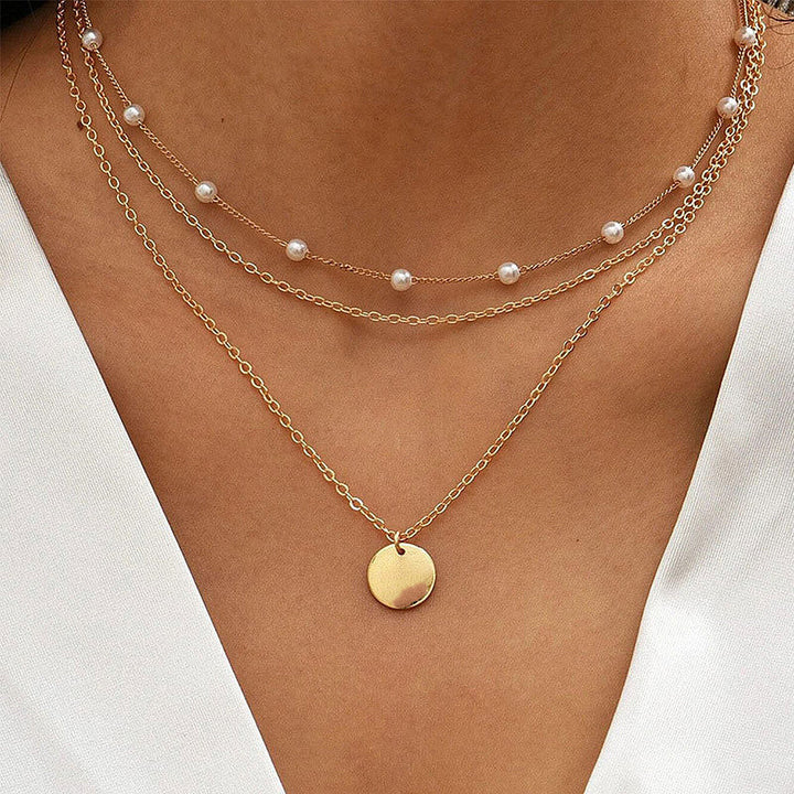 Elegant women's layered necklace featuring white pearls and delicate gold chains.