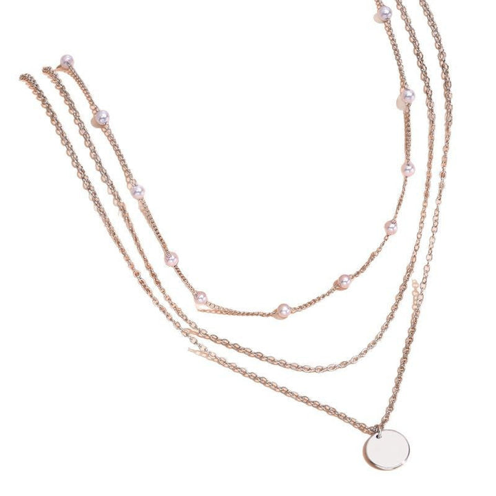 Close-up of a sophisticated women's layered pearl and gold chain necklace, a timeless piece.