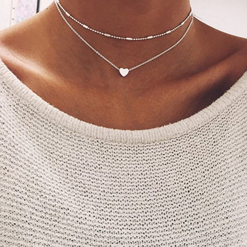 Elegant women's layered necklace with a delicate heart charm, perfect for versatile styling. Gold or silver.